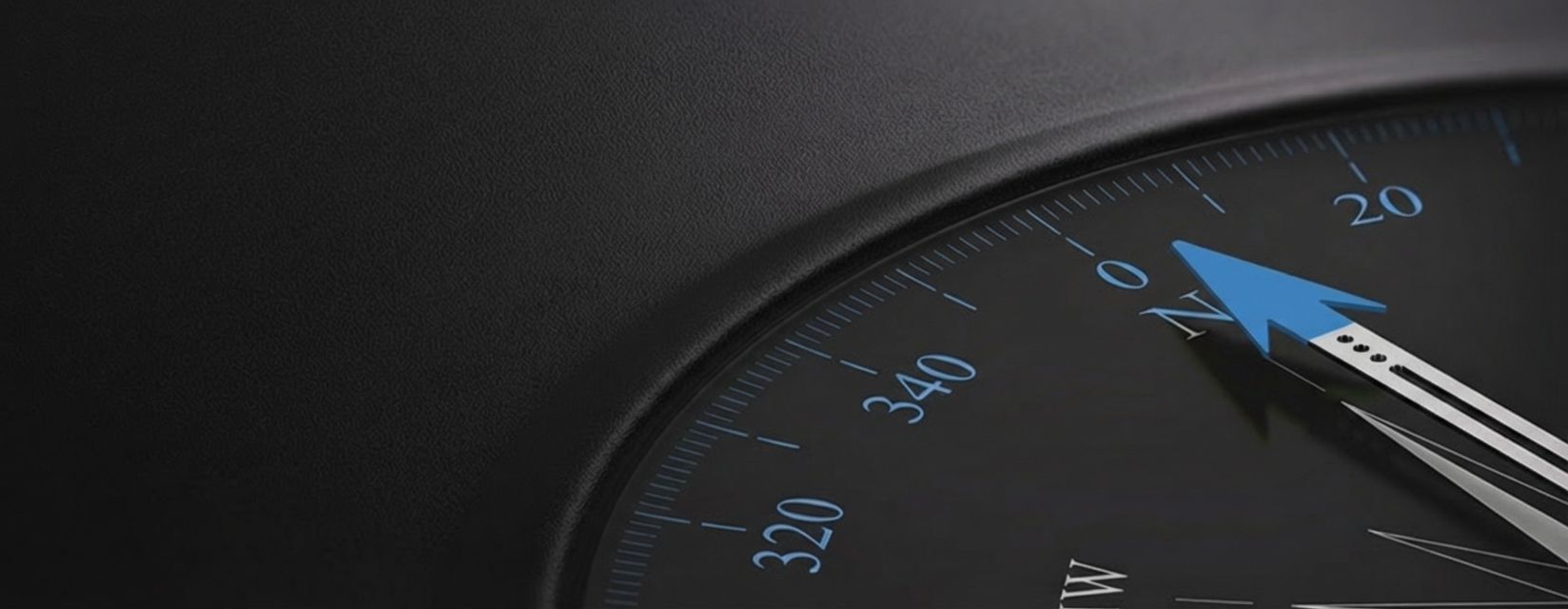 Close-up photography of a compass, with green arrow pointing north, in a dark background